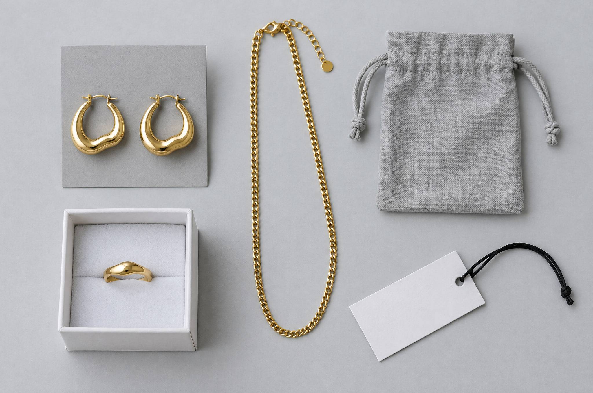 Unbranded private-label packaging: hoops on a grey card, a ring in a white box, a chain, a grey cotton pouch and a blank hang tag.